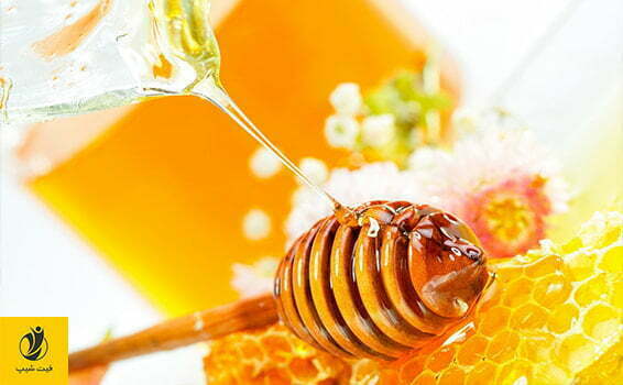 عکس یه قاشق چوبی مخصوص عسل که روی یک موم عسل قرار گرفته و از بالا روی آن عسل در حال ریختن است.- ژن سبز