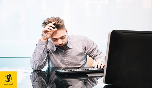 عکس مرد جوانی که در پشت میزکار خود به دلیل استرسی که دارد، دچار خستگی دائم است و دست از کار کشیده به صفحه کلید کامپیوتر خود خیره شده است- ژن سبز