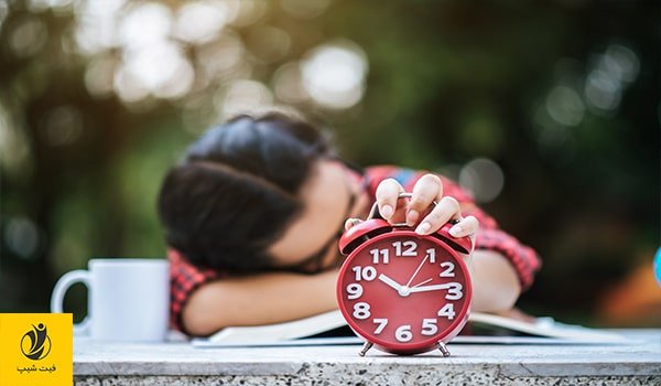 عکس خانمی که در اثر رژیم غذایی نامناسب، دچار خستگی دائم شده مدام ساعت در حال زنگ را خاموش می کند که کمی بیشتر بخوابد- ژن سبز